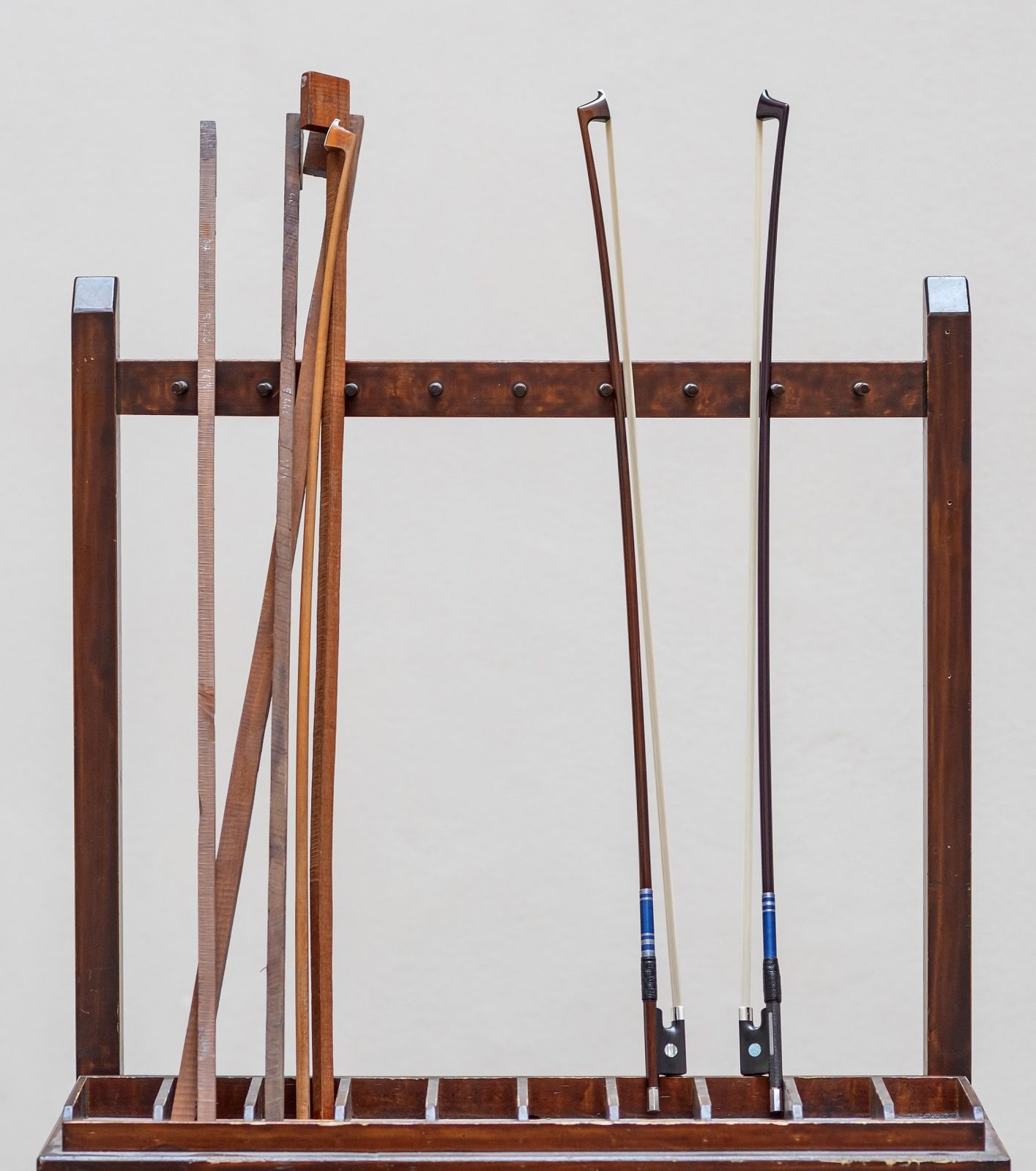 Bow rack holding square-cut blanks and a roughed-out stick on the left, two finished bows on the right