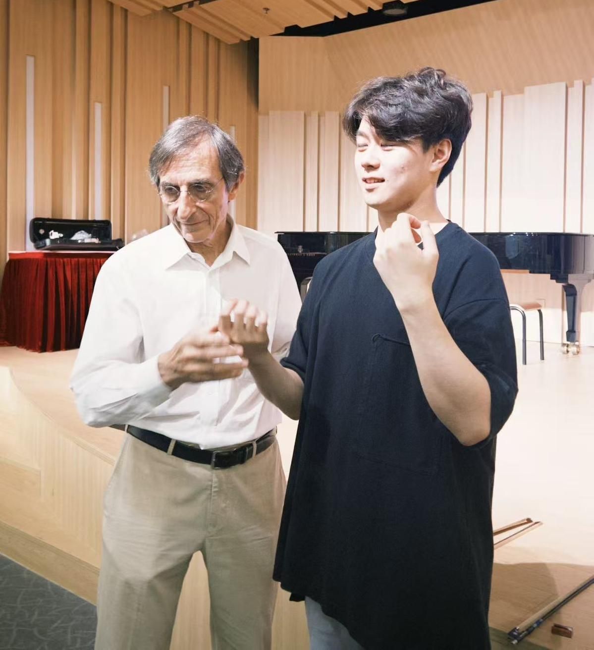 Gilles Saurais and a student facing each other, comparing hand positions without instruments