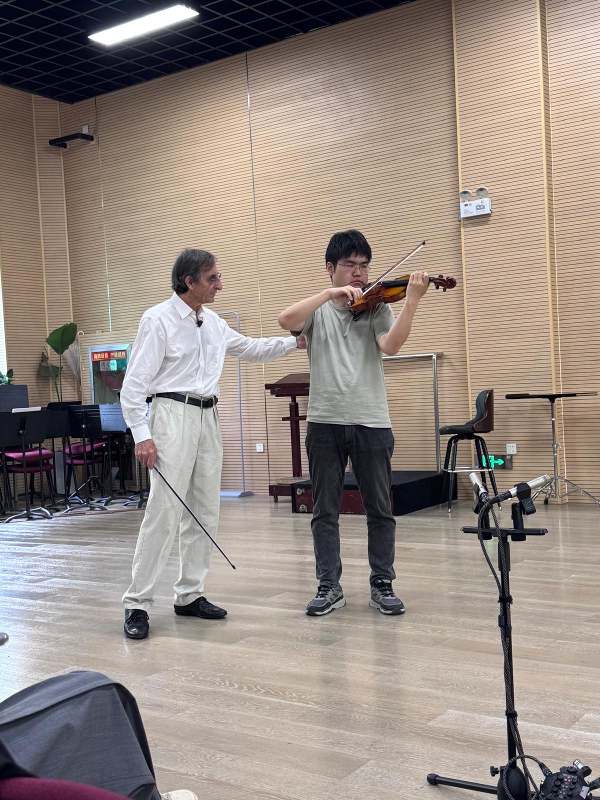 Gilles Saurais with a hand on a violinist's shoulder, recording microphones in the foreground