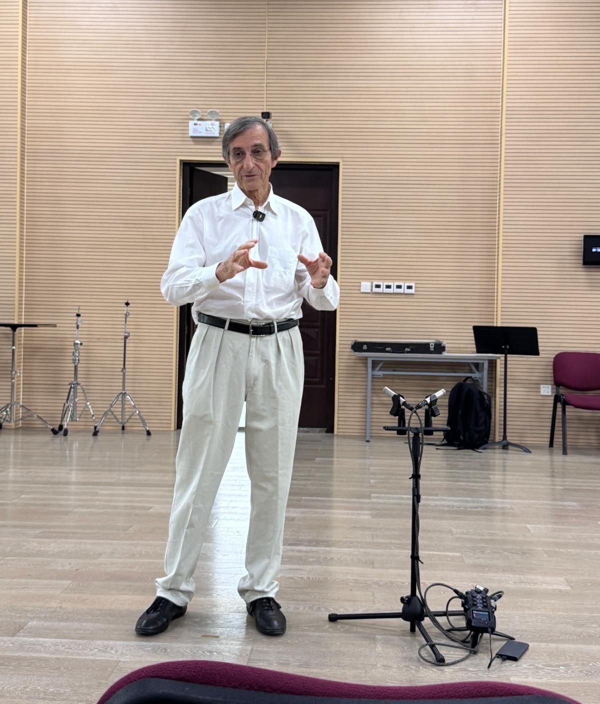 Gilles Saurais speaking in a rehearsal room next to a recording microphone stand